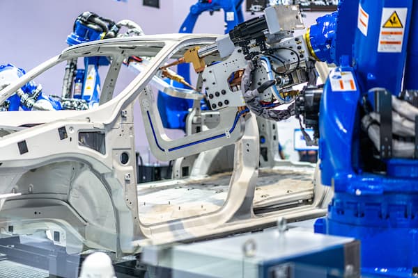Automated drill creating holes in a multi-material automotive A-pillar during car frame fabrication.