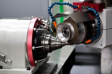 Nahaufnahme einer CNC-Maschine mit einem Bohrer, der in der Nähe eines Metallwerkstücks positioniert ist.