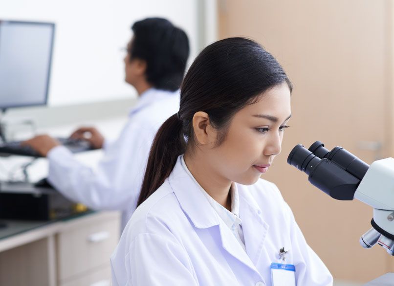 woman at microscope performing research and development